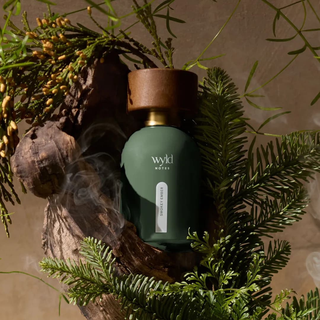 Smokey Ember de Wyld Notes entre ramas de coníferas con humo ascendente