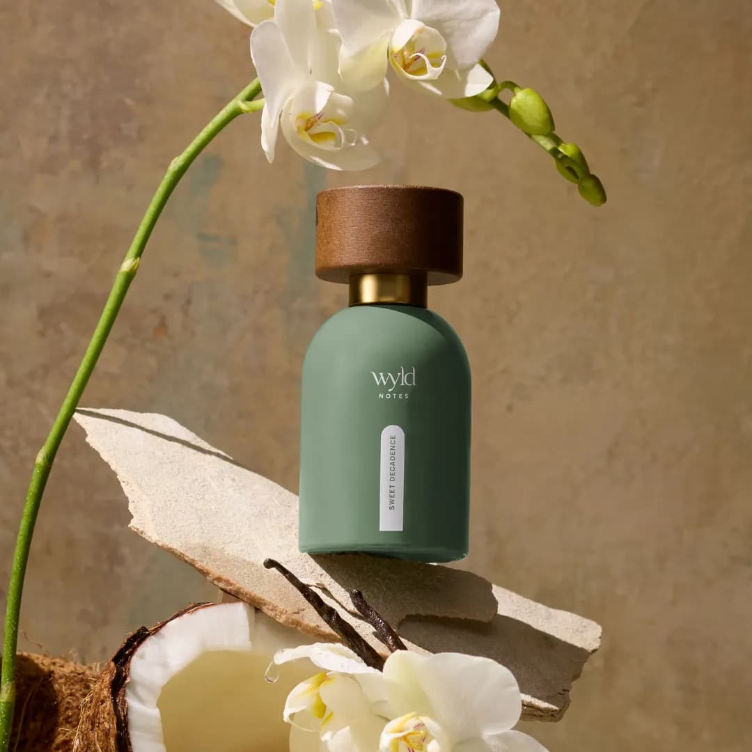 Sweet Decadence de Wyld Notes junto a una orquídea y un coco abierto