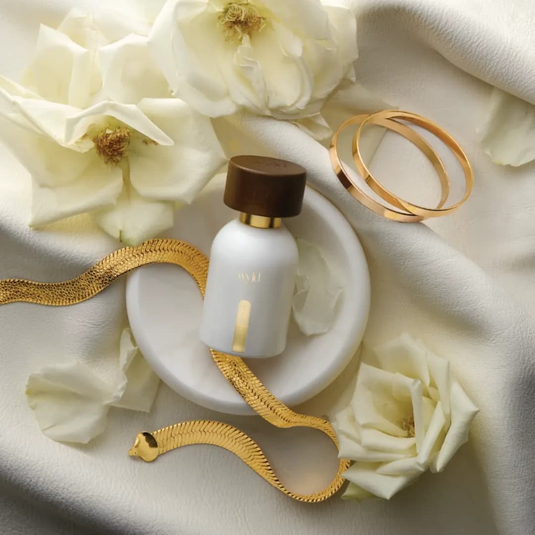 White Lie de Wyld Notes entre rosas blancas y una pulsera dorada